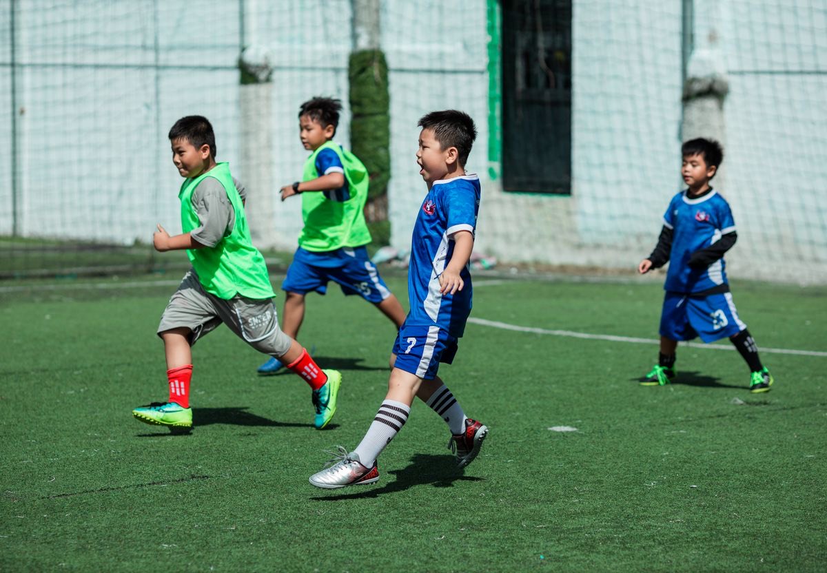 Young soccer players in a mix of green practice pinnies and blue jerseys during a scrimmage