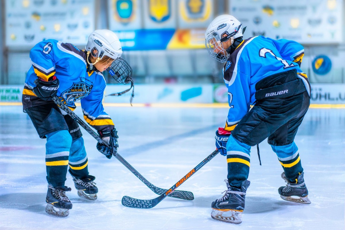 Young ice hockey players facing off on indoor rink ice