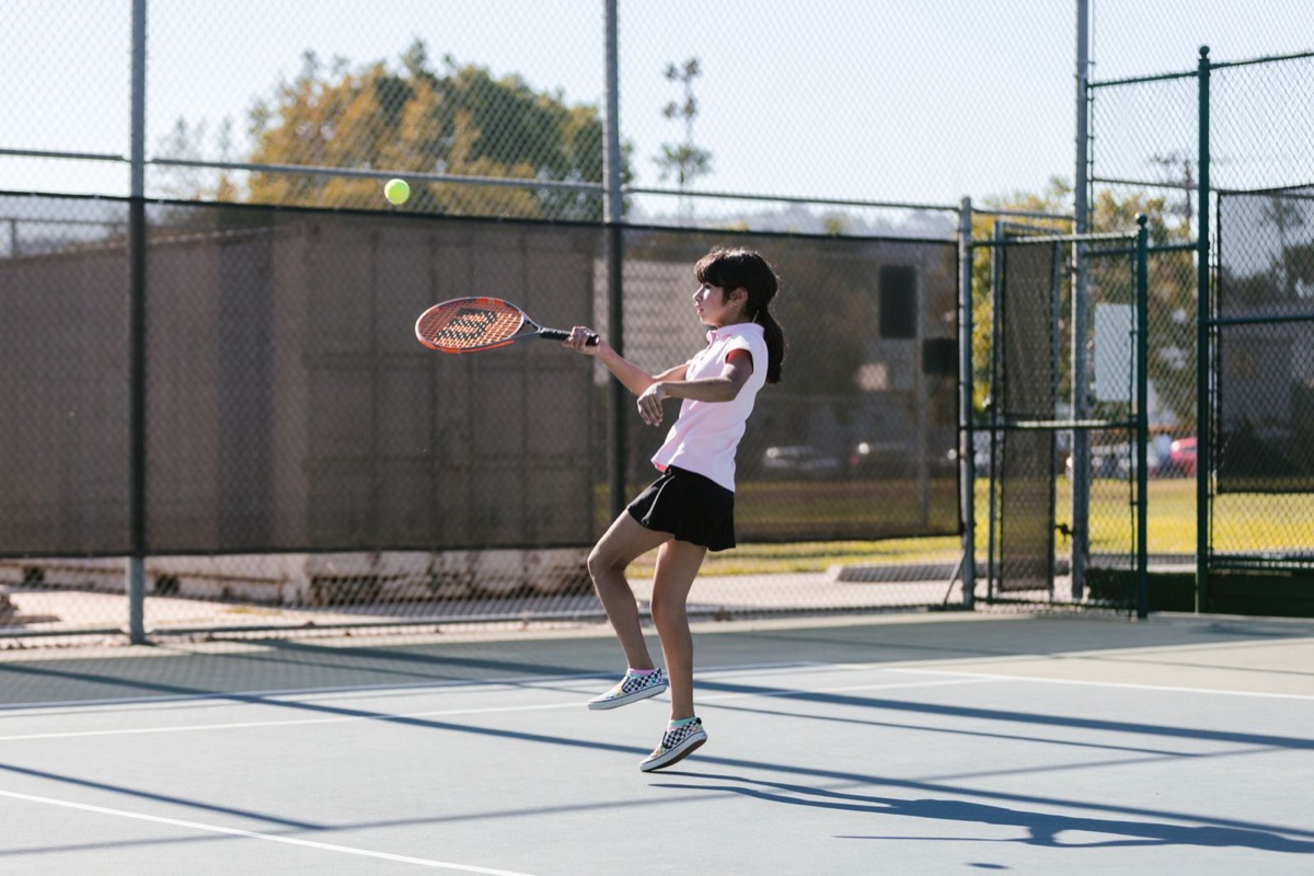 Junior tennis player hitting a forehand on an outdoor court