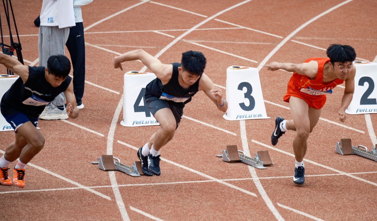 Sprinters bursting out of the starting blocks at a track meet